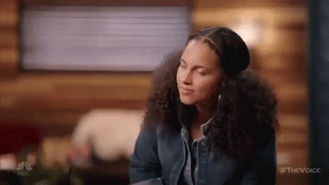 A Woman With Curly Hair Is Wearing Headphones And A Hat While Sitting In A Cabin . GIF