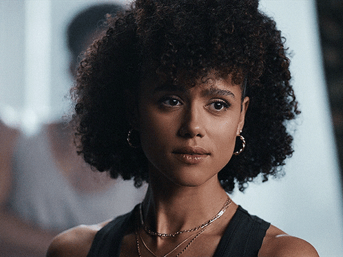 A Woman With Curly Hair Is Wearing Hoop Earrings GIF