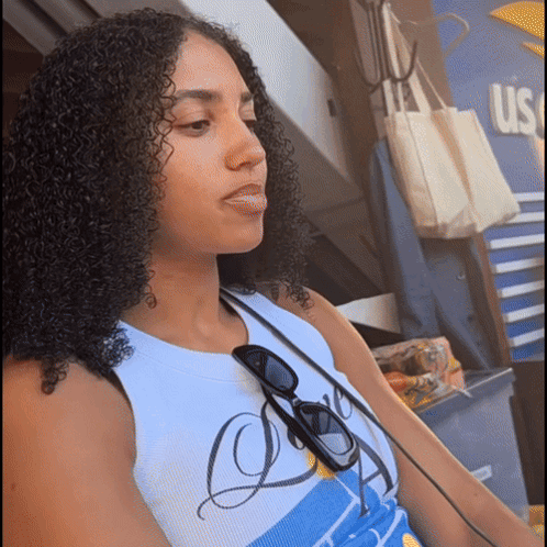 A Woman With Curly Hair Is Wearing Sunglasses And A Shirt That Says Us GIF