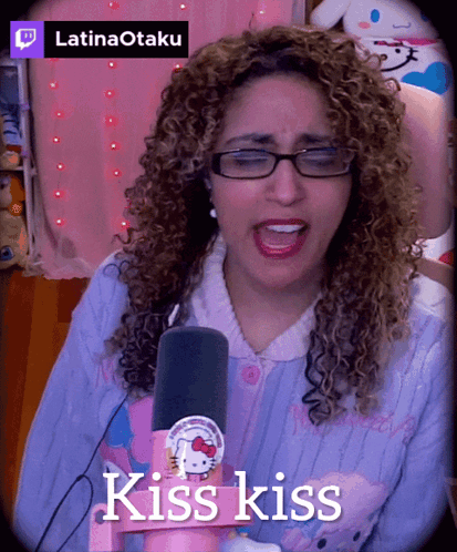 A Woman With Curly Hair Singing Into A Microphone With The Words Kiss Kiss Above Her GIF