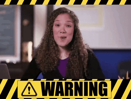 A Woman With Curly Hair Stands In Front Of A Warning Sign GIF