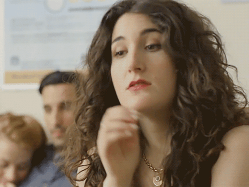 A Woman With Curly Hair Wearing A Gold Necklace GIF