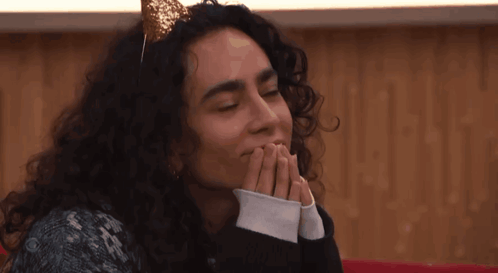 A Woman With Curly Hair Wearing A Headband With A Gold Bow On It GIF