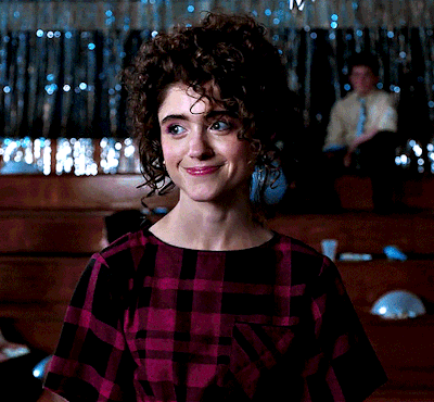 A Woman With Curly Hair Wearing A Purple Plaid Shirt GIF