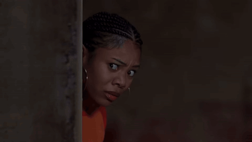 A Woman With Dreadlocks And Hoop Earrings Is Leaning Against A Wall GIF