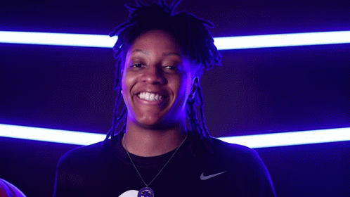 A Woman With Dreadlocks Is Holding A Basketball And Smiling For The Camera GIF