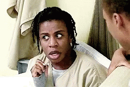 a woman with dreadlocks is sitting next to a man in a prison cell and making a funny face .