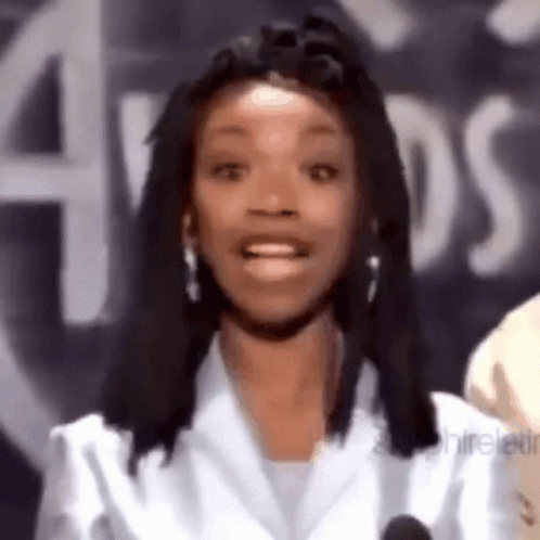 A Woman With Dreadlocks Is Smiling In Front Of A Sign That Says Aids GIF