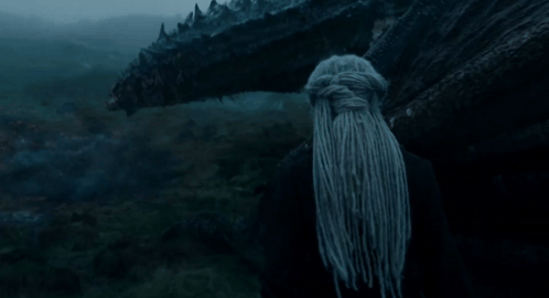 a woman with dreadlocks stands in front of a monster