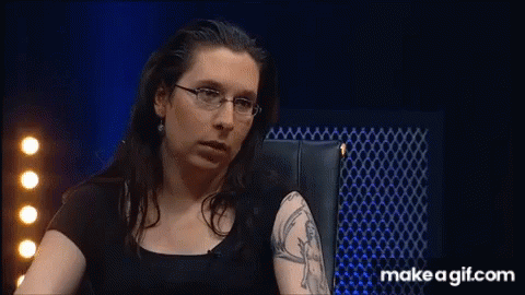 A Woman With Glasses And A Tattoo On Her Arm Is Sitting In A Chair GIF