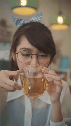 A Woman With Glasses Is Drinking From A Glass GIF