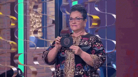 A Woman With Glasses Is Holding A Sign That Says M On It GIF