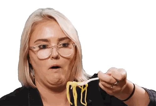 a woman with glasses is holding a spoon with noodles on it
