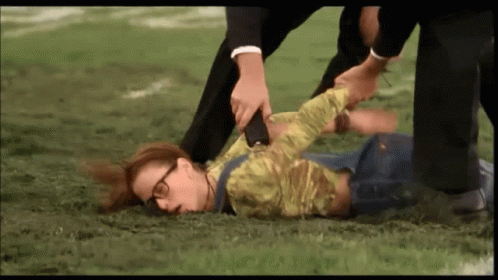 A Woman With Glasses Is Laying On The Ground While A Man Holds Her Arm GIF