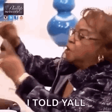 A Woman With Glasses Is Sitting At A Table With Her Hands In The Air And Says I Told Yall . GIF