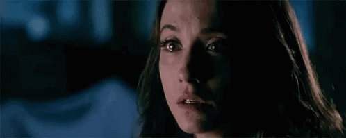 A Woman With Glowing Eyes Is Looking At The Camera In A Dark Room . GIF