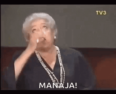 A Woman With Gray Hair Is Holding A Glass Of Water In Her Hand And Says `` Manaja '' . GIF