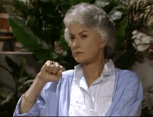 A Woman With Gray Hair Is Wearing A Blue Cardigan And White Shirt GIF