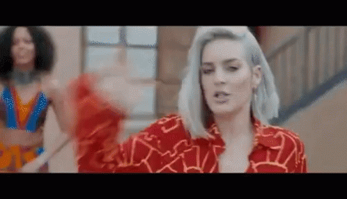 A Woman With Gray Hair Is Wearing A Red Shirt And Dancing On A Staircase . GIF