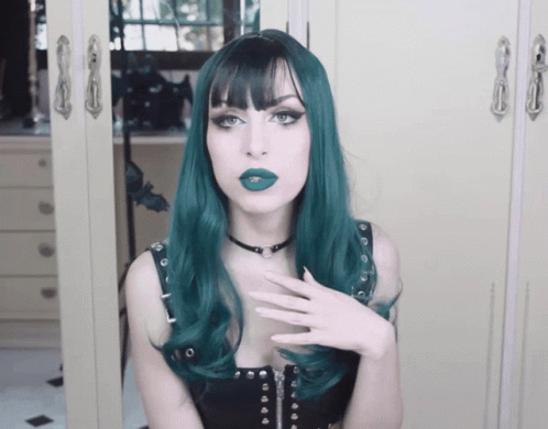 A Woman With Green Hair And A Black Choker Looks At The Camera GIF