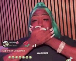 A Woman With Green Hair Is Covering Her Mouth In Front Of A Wooden Wall GIF