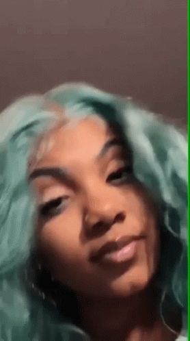 A Woman With Green Hair Is Smiling For The Camera . GIF