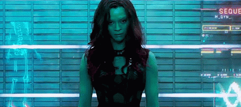 A Woman With Green Hair Is Standing In Front Of A Wall With A Sign That Says Seque GIF