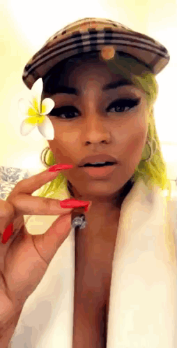 A Woman With Green Hair Is Wearing A Hat And Holding A Flower To Her Face . GIF