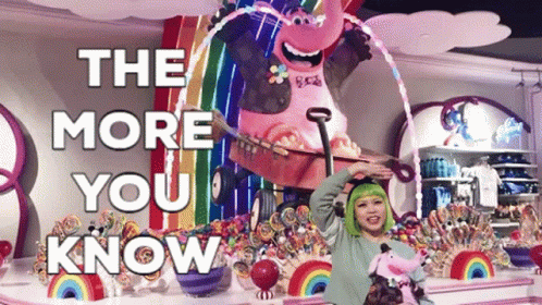 A Woman With Green Hair Stands In Front Of A Display Of Candy And A Sign That Says " The More You Know " GIF