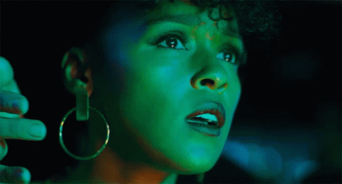A Woman With Green Paint On Her Face Is Looking Up GIF