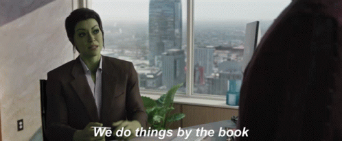 Green Woman Sitting At Desk With We Do Things By The Book GIF