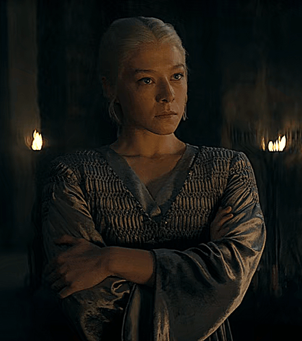 a woman with her arms crossed and her eyes closed stands in a dark room