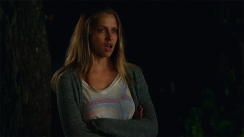 A Woman With Her Arms Crossed Is Wearing A Gray Cardigan GIF