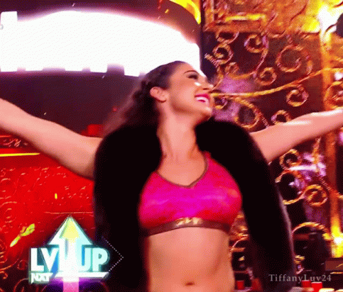 A Woman With Her Arms Outstretched In Front Of A Sign That Says Lvvip GIF