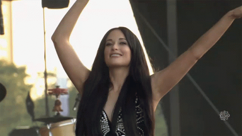 A Woman With Her Arms Outstretched Is Smiling In Front Of A Sign That Says ' I Love You ' GIF
