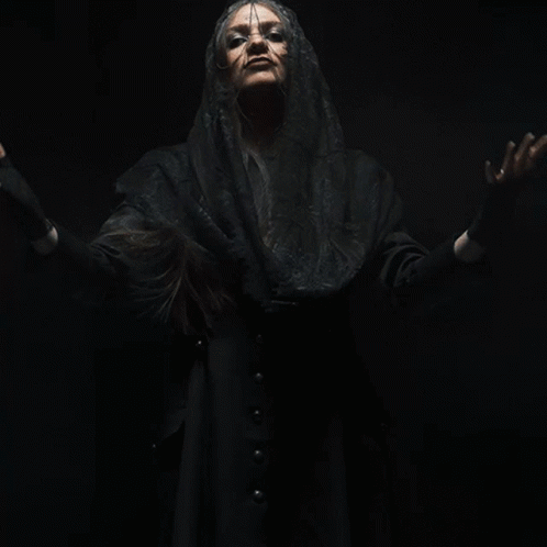 A Woman With Her Arms Outstretched Is Wearing A Black Veil And Black Gloves GIF