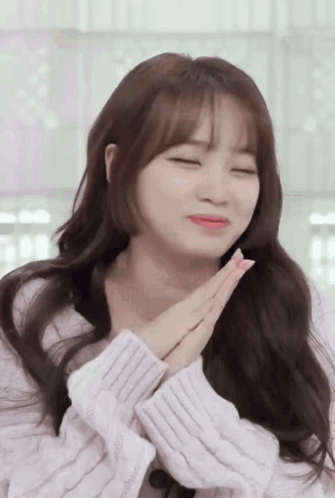 A Woman With Her Eyes Closed And Her Hands Folded In Front Of Her Face GIF