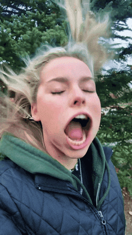 A Woman With Her Eyes Closed And Her Tongue Out GIF