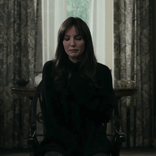 A Woman With Her Eyes Closed Is Sitting In A Chair In Front Of A Window GIF