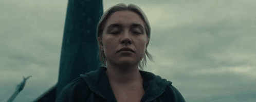 A Woman With Her Eyes Closed Is Standing In Front Of A Pole In The Dark . GIF