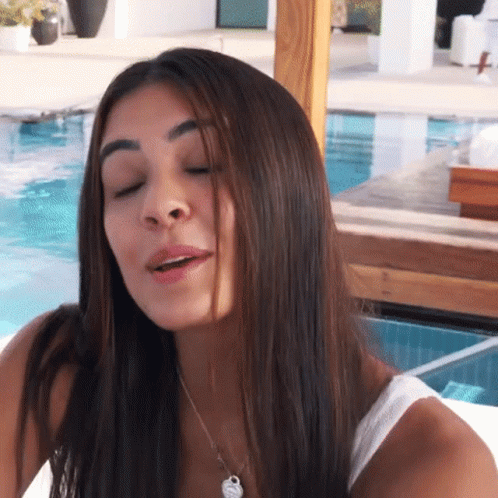 A Woman With Her Eyes Closed Is Wearing A White Tank Top And A Necklace GIF