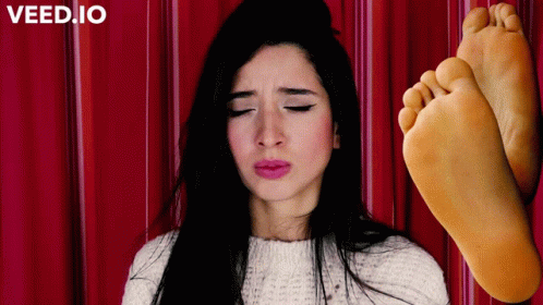 A Woman With Her Eyes Closed Next To A Pair Of Feet With The Word Veed.io On The Bottom Left GIF