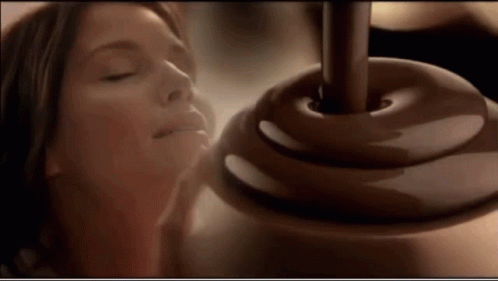 A Woman With Her Eyes Closed Smelling A Chocolate Covered Object GIF