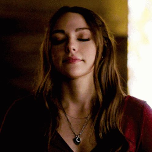 A Woman With Her Eyes Closed Wearing A Necklace With A Heart Shaped Pendant GIF