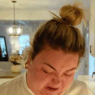 A Woman With Her Hair In A Bun Is Making A Face . GIF