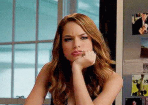 A Woman With Her Hand On Her Chin Is Sitting In Front Of A Window . GIF