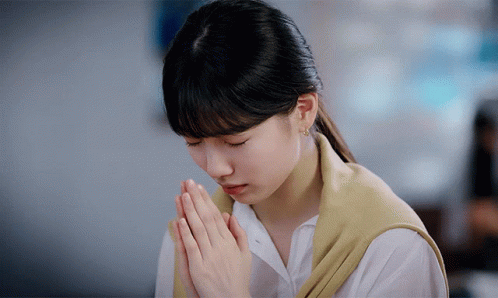 A Woman With Her Hands Folded In Prayer GIF