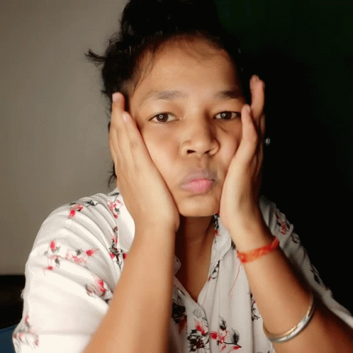 A Woman With Her Hands On Her Face Is Wearing A Red Bracelet GIF