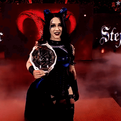 A Woman With Horns Is Holding A Trophy In Front Of A Sign That Says Stey GIF