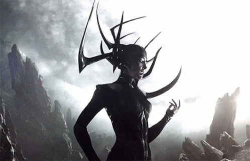 A Woman With Horns On Her Head Stands In Front Of A Mountain GIF